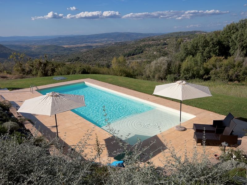 Piscina rinnovata con scala romana in un giardino in collina