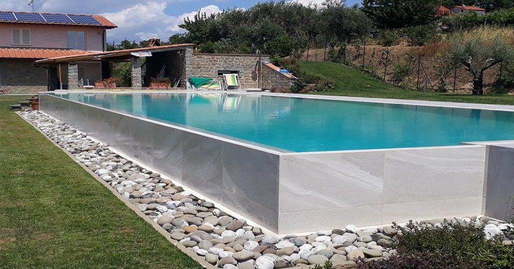 Piscina a sfioro rialzata rivestita in pietra