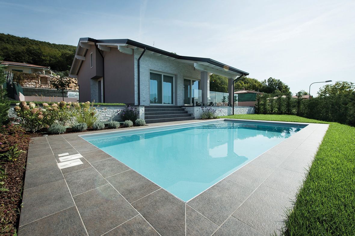 Piscina a skimmer con bordo in pietra grigia